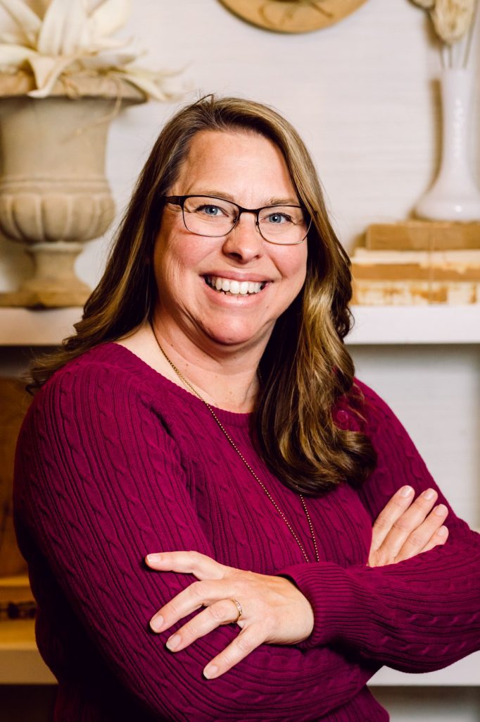 Sharon R Page, Conversion Copywriter & Messaging Strategist, smiling in glasses and maroon sweater with arms crossed