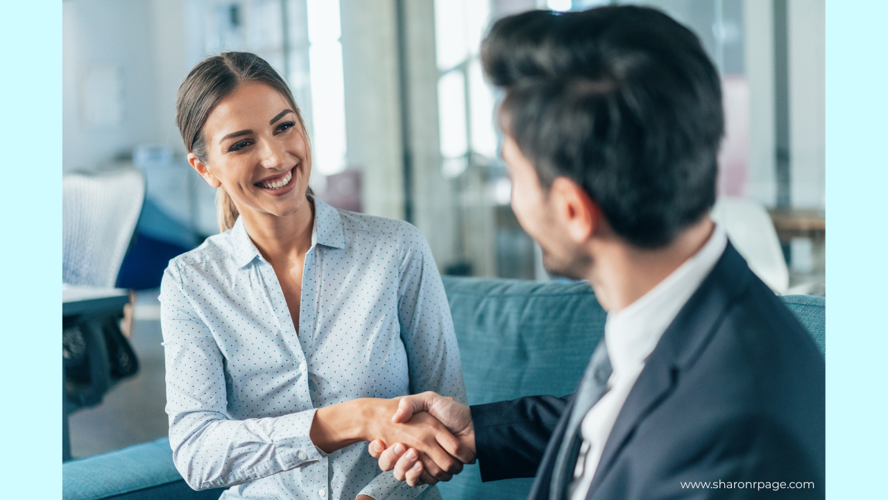 Smiling businesswoman shaking hands with a male colleague during a meeting in a modern office.