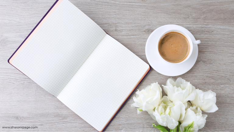 Flat lay of an open grid notebook, cup of espresso, and white tulips on a light wood desk — a clean, calming workspace for reflection or writing.