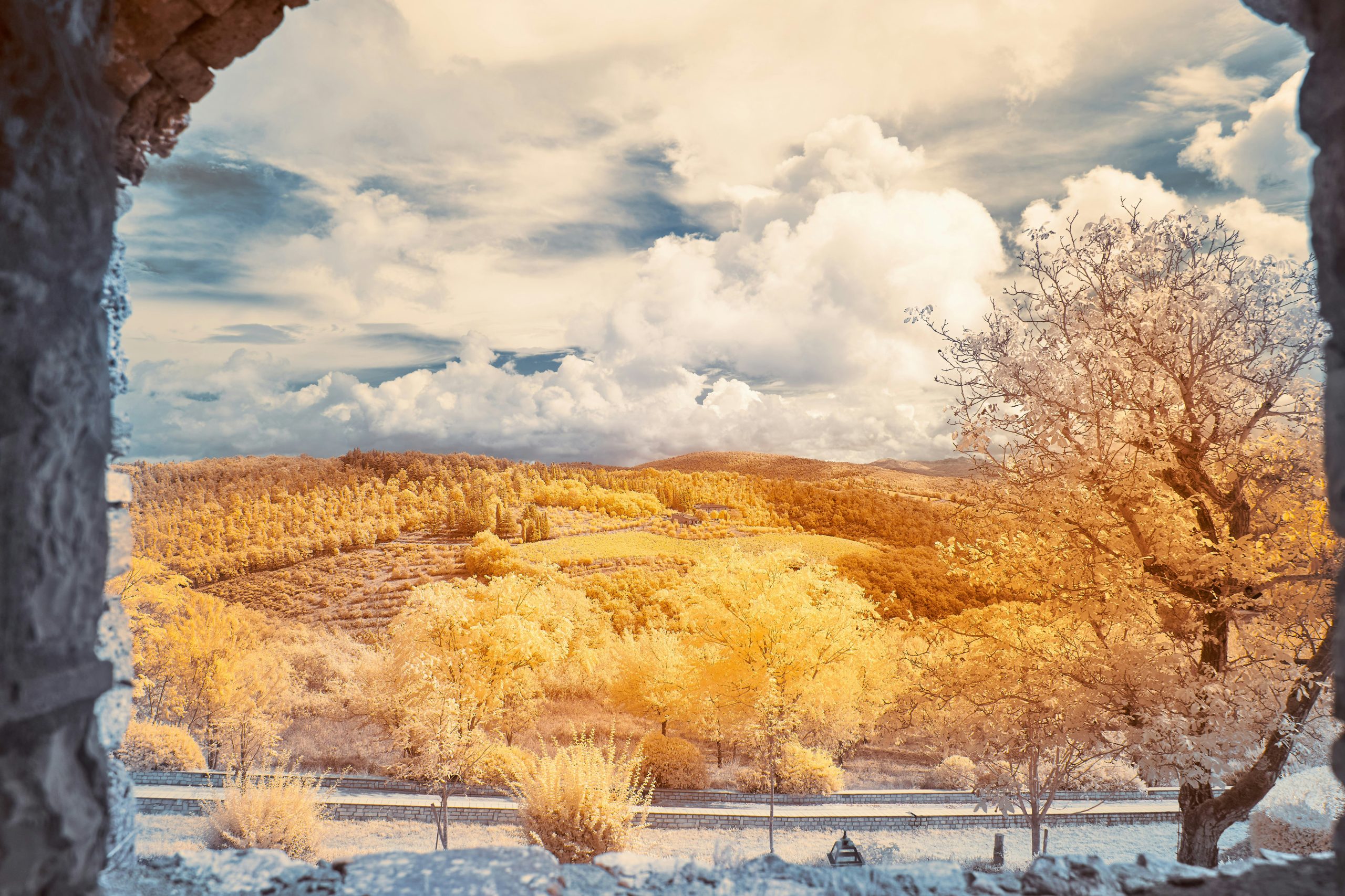 Looking out from a stone window onto golden trees and rolling hills under a dramatic sky — a scenic view symbolizing higher perspective and vision.